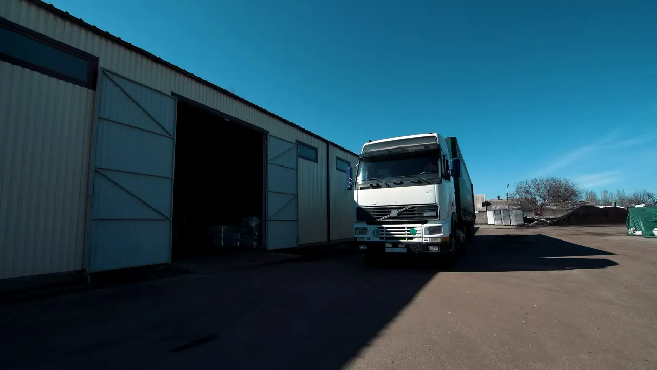 Camion blanc avec semi-remorque sortant d’un entrepôt